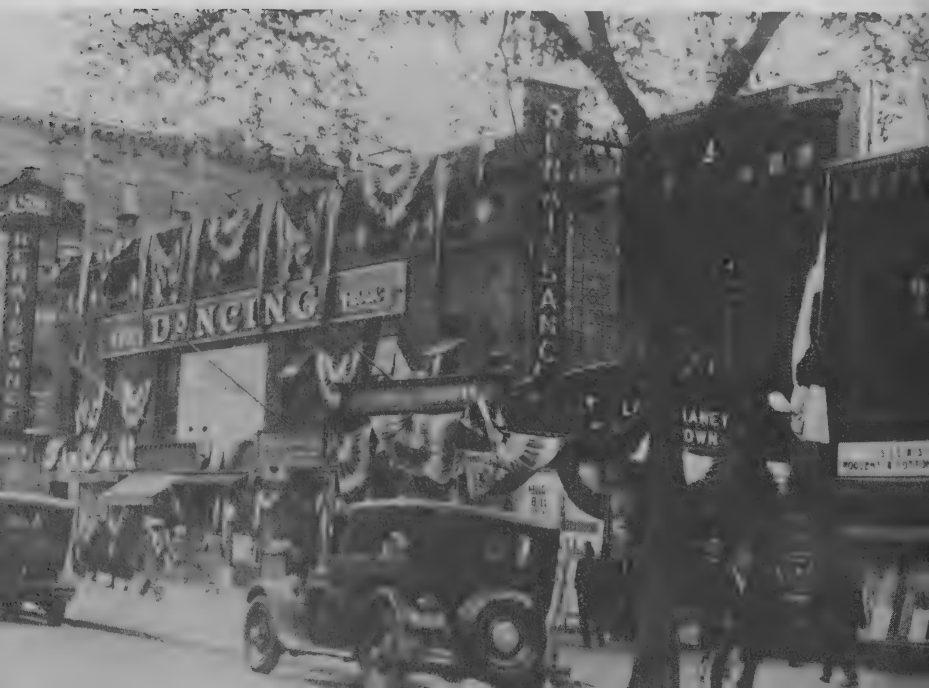 Harlem street photograph showing the Renaissance Casino ballroom building, dancing signs, pedestrians, and cars, 1927.